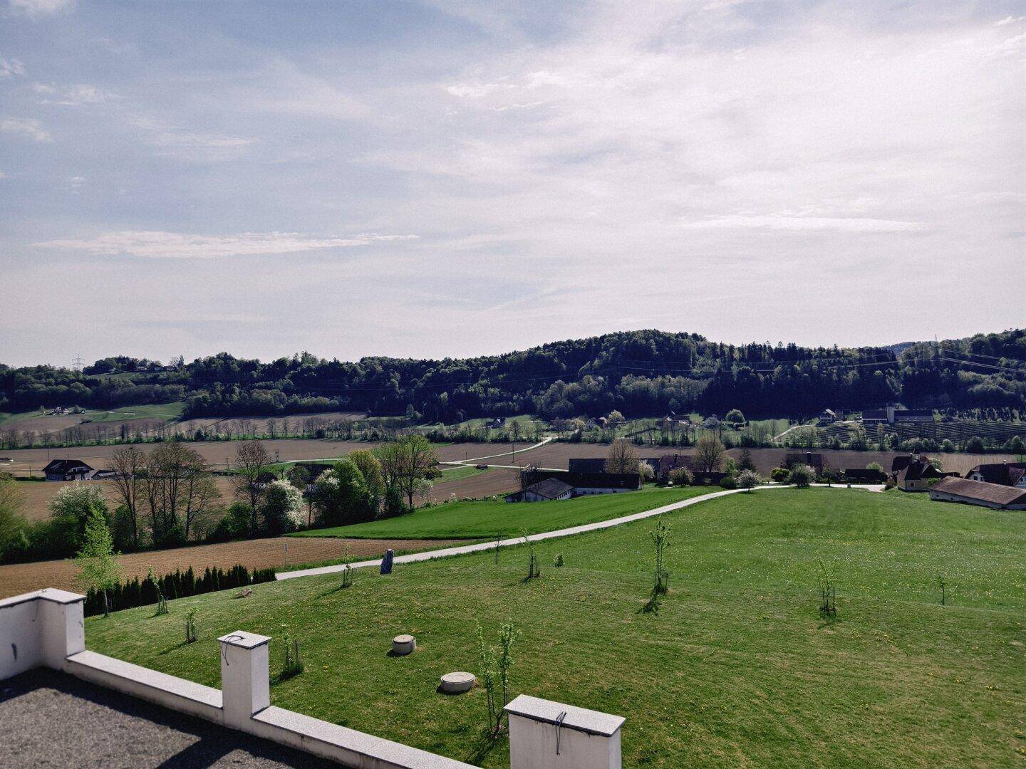 Weitläufiger Blick von der Terrasse über die grüne Landschaft und die umliegenden Felder.