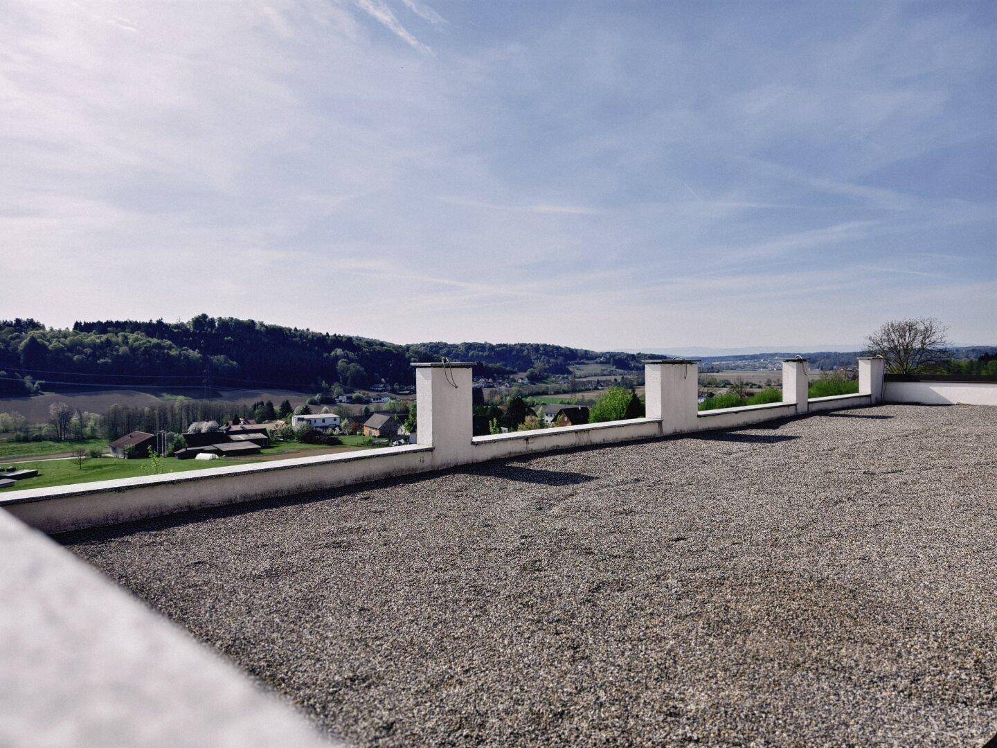 Große Dachterrasse mit Kiesbelag und weitem Panoramablick über die ländliche Umgebung.