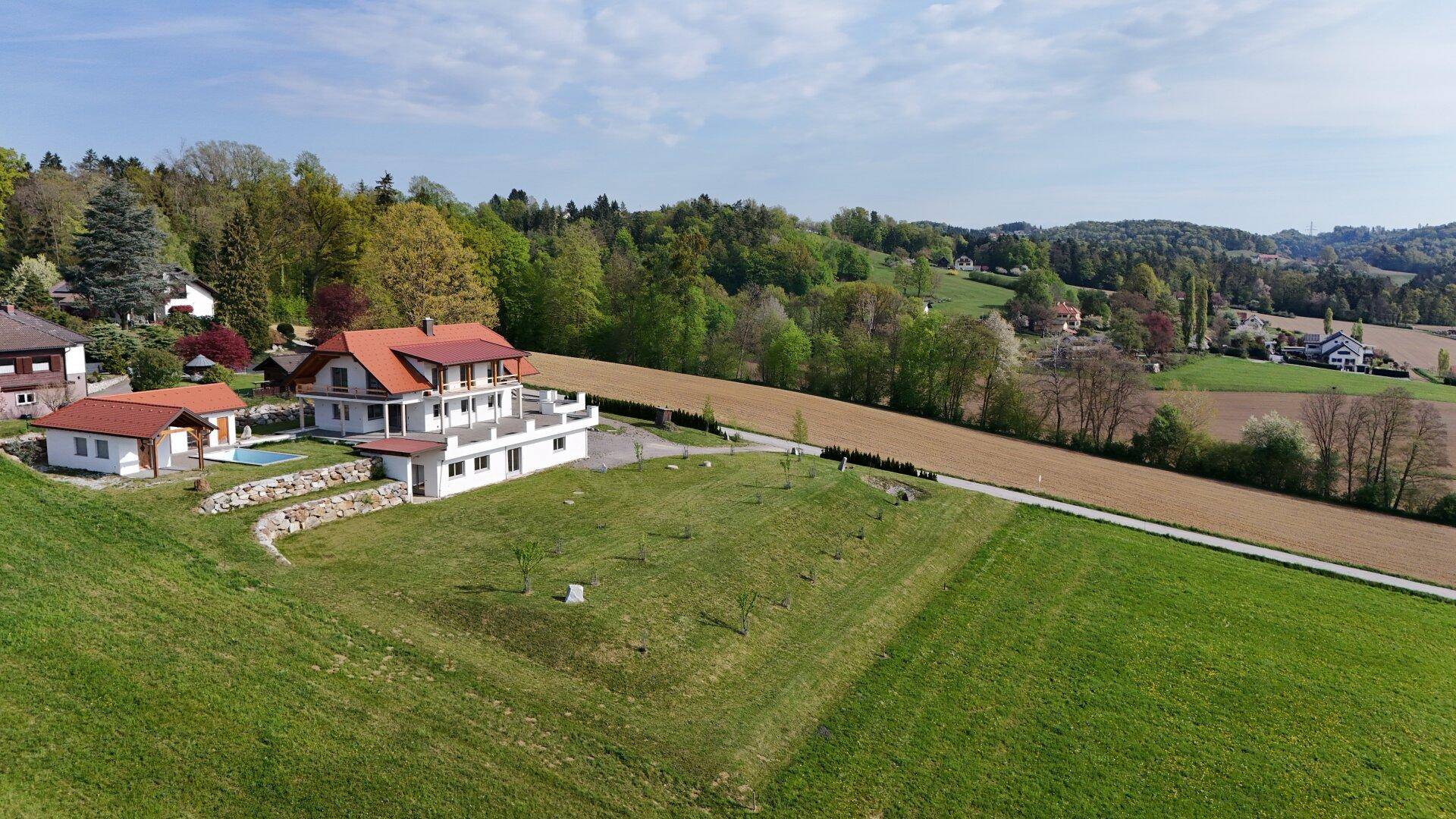 Luftaufnahme des Anwesens mit Hauptgebäude, Nebengebäude, Pool und weitläufiger Grünfläche in ländlicher Idylle.