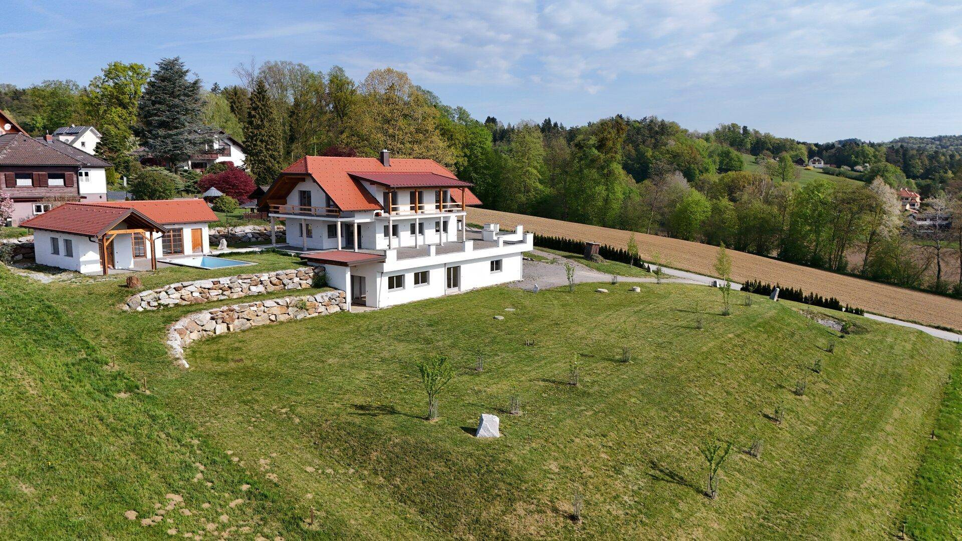 Weitläufiges Anwesen mit Hauptgebäude, Nebengebäude, Pool und weitläufiger Grünfläche in ländlicher Idylle.