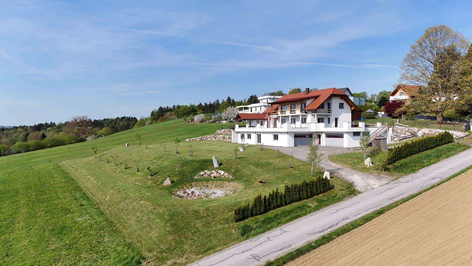 Weitläufiges Anwesen mit modernem Haus, großem Garten und angrenzenden Feldern in ländlicher Umgebung.