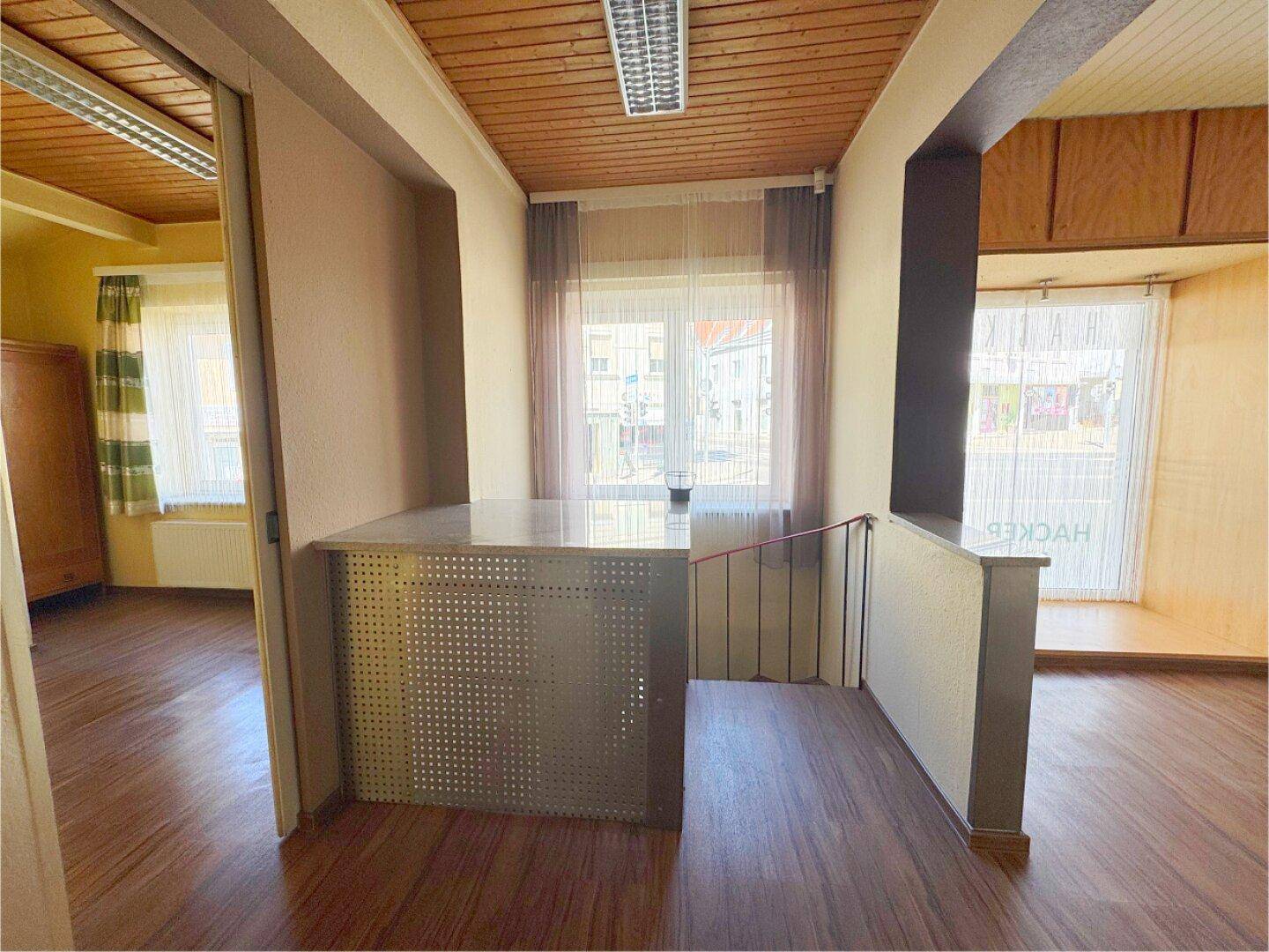 Flur mit Holzdecke und Holzfußboden, der zu weiteren Räumen führt und Tageslicht erhält.