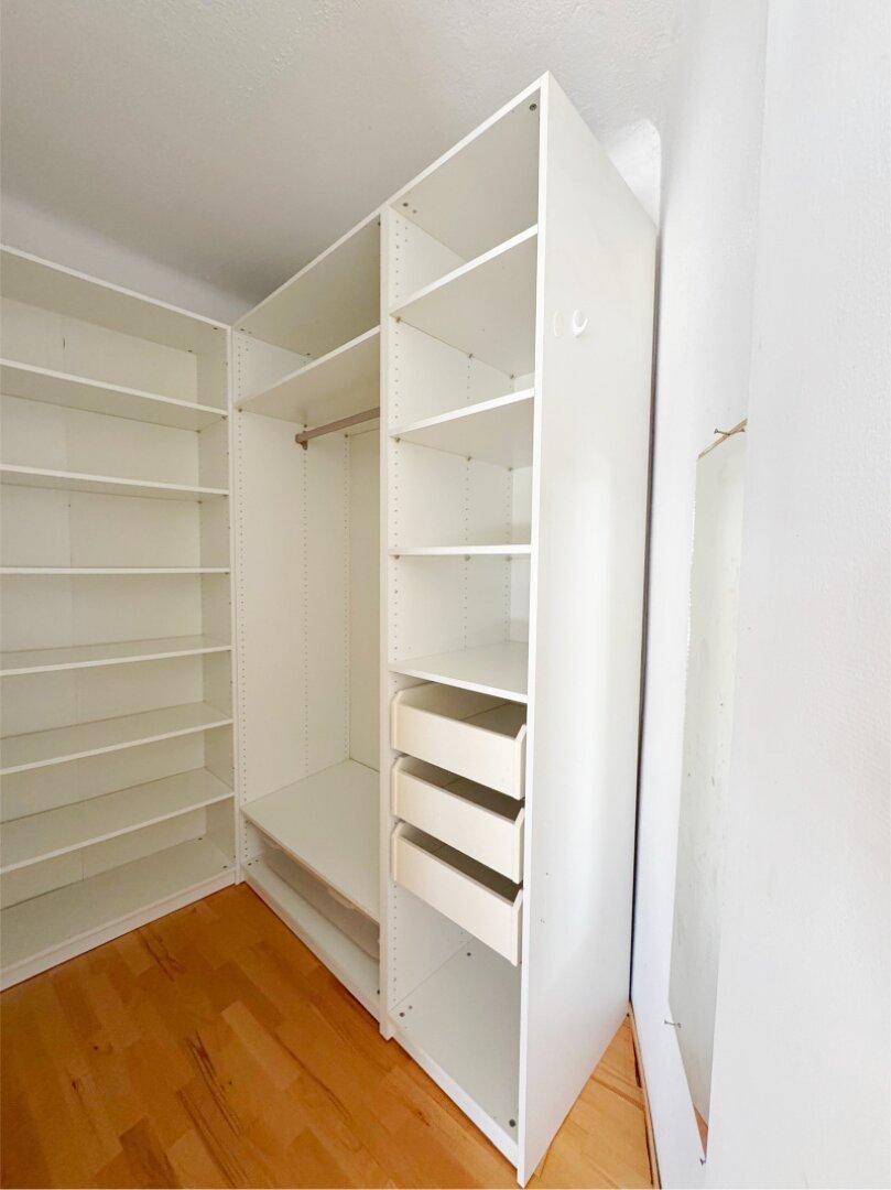 Begehbarer Kleiderschrank mit weißen Regalen und Schubladen für viel Stauraum.