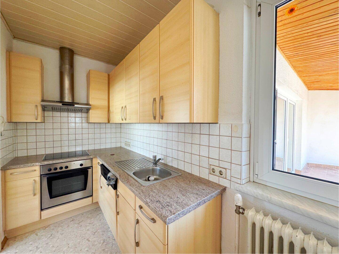 Küche mit hellen Holzschränken, Granit-Arbeitsplatte und Blick nach draußen.