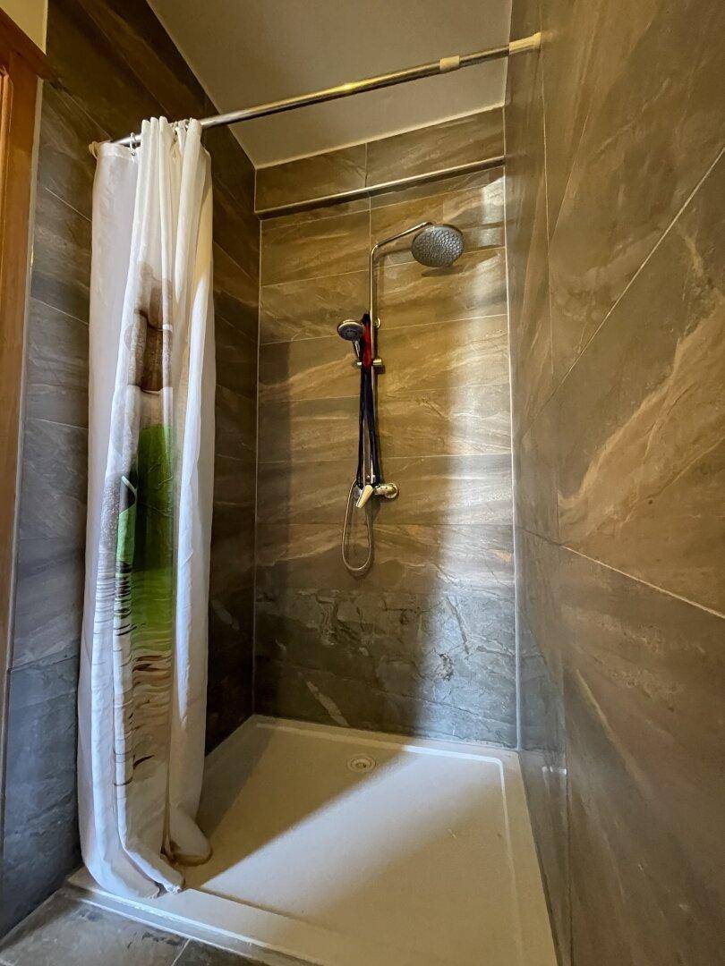 Duschkabine mit Duschvorhang und modernen Fliesen in einem funktionalen Badezimmer.