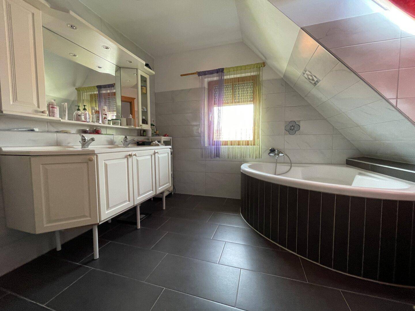 Geräumiges Badezimmer im Dachgeschoss mit Eckbadewanne, Doppelwaschbecken und Dachfenster.