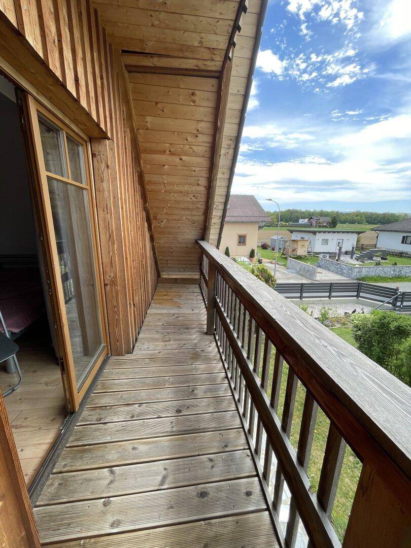 Langer Holzbalkon mit Geländer und Blick auf die Umgebung und andere Häuser.