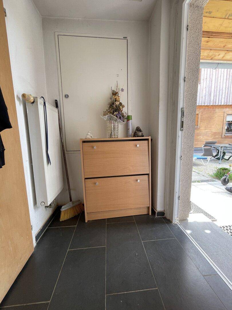 Eingangsbereich mit Schuhschrank, Heizkörper und dunklem Fliesenboden, führt direkt ins Freie.