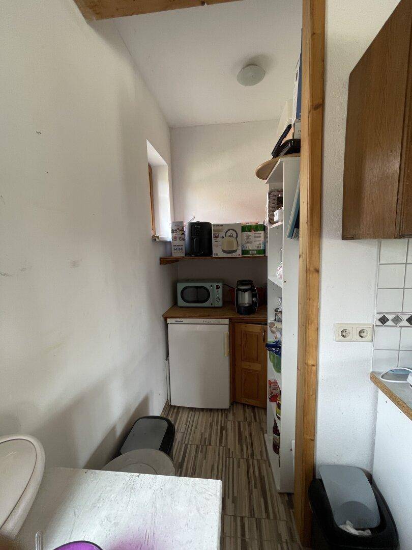 Kleiner Hauswirtschaftsraum mit Minikühlschrank, Mikrowelle und Regalen für zusätzlichen Stauraum.