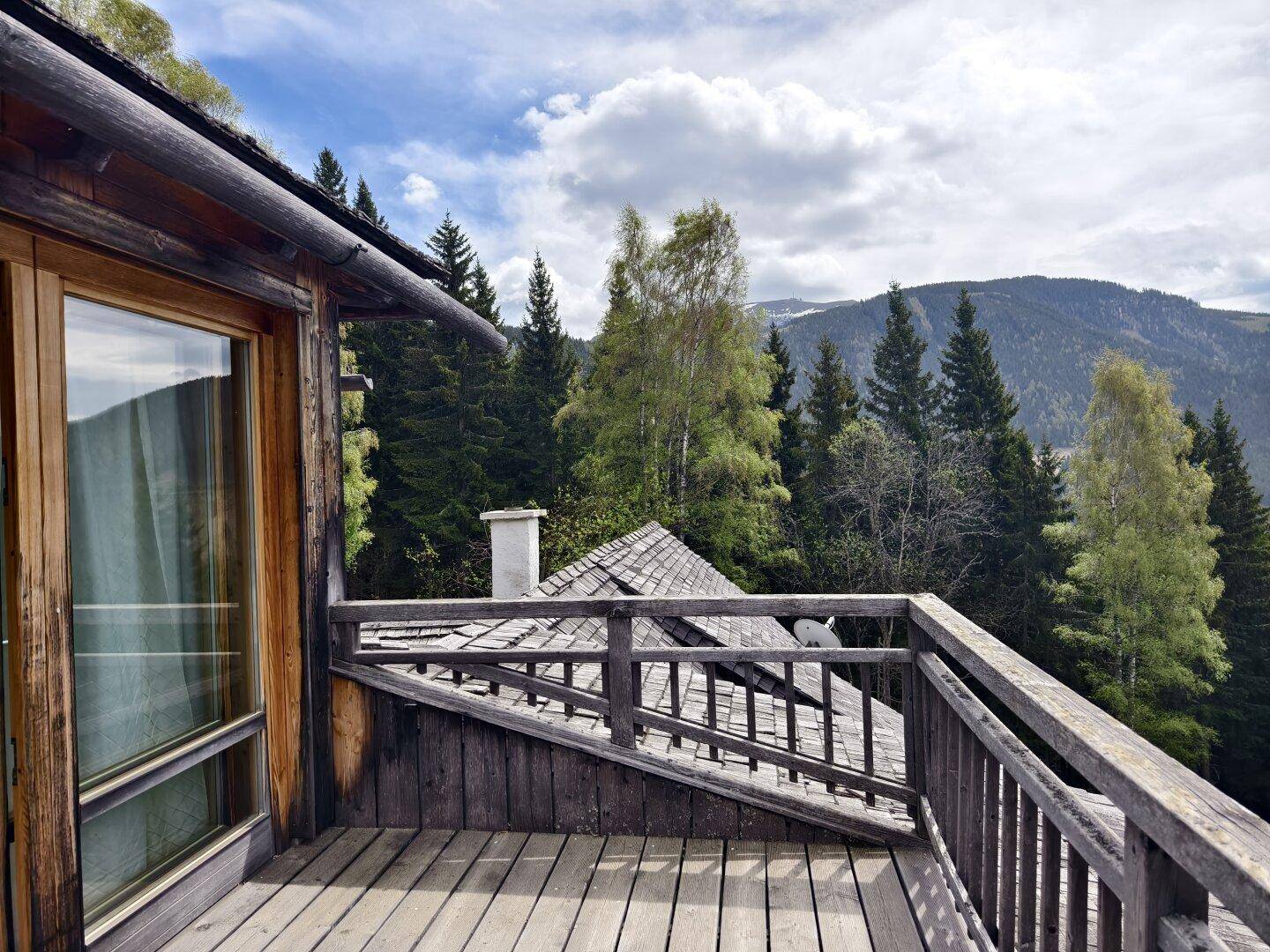 Geräumiger Holzbalkon mit rustikalem Geländer und atemberaubendem Blick auf die Berge.