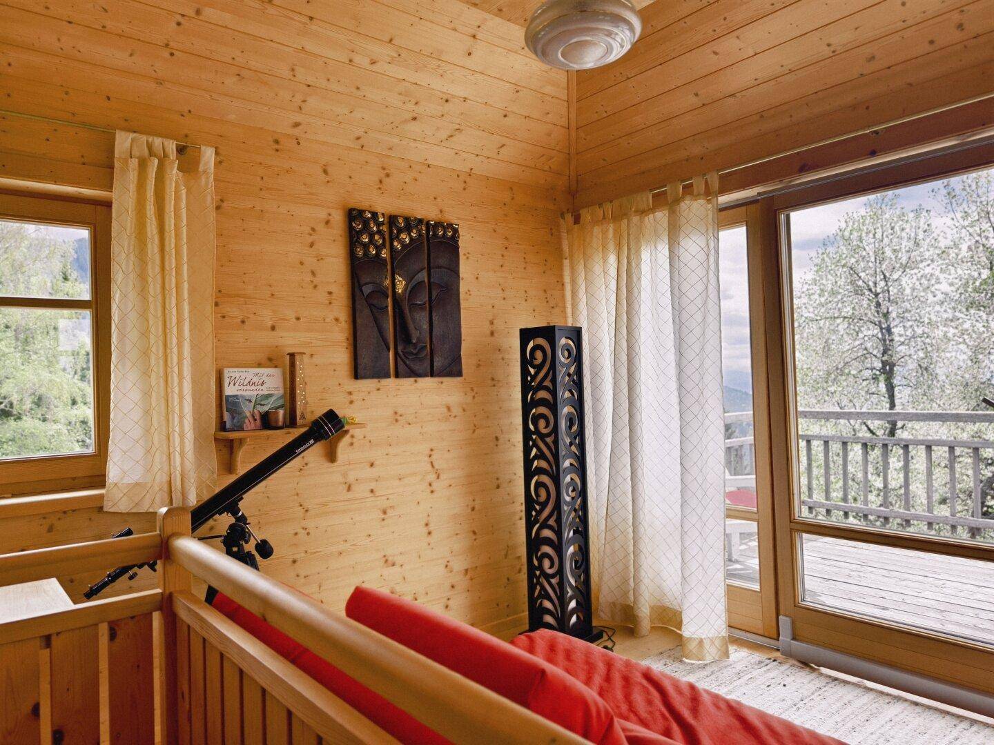 Helles Schlafzimmer mit Holzvertäfelung, Balkonzugang und Blick auf die Natur.
