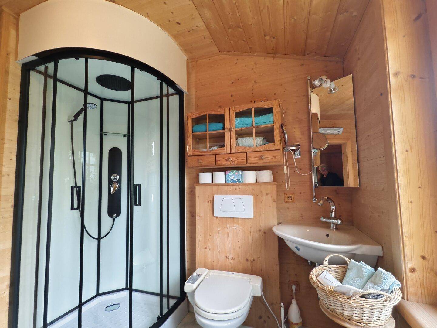 Rustikales Badezimmer mit Holzvertäfelung, Duschkabine und praktischem Waschbecken.