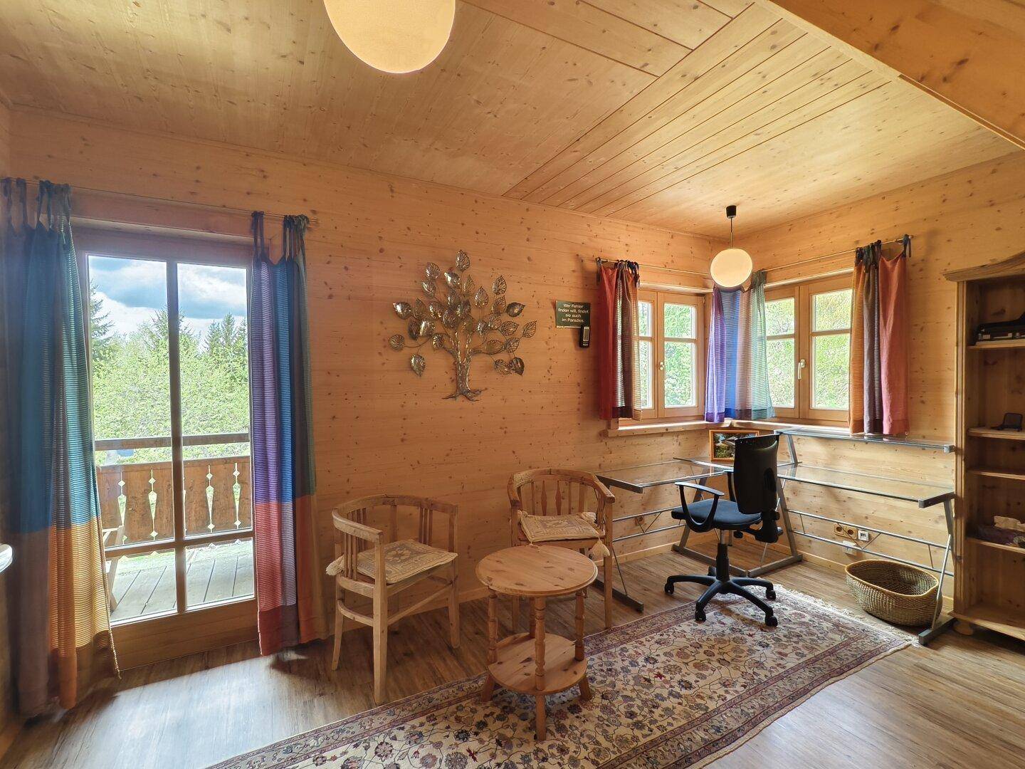 Helles Arbeitszimmer mit Holzvertäfelung, Schreibtisch und Zugang zu einem Balkon.