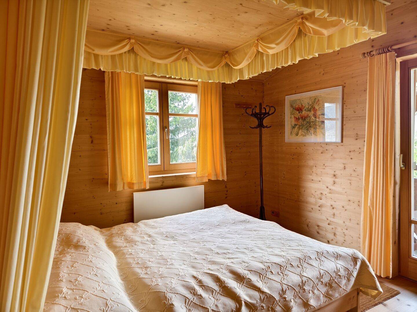 Komfortables Schlafzimmer mit Holzvertäfelung, Doppelbett und traditioneller Dekoration.