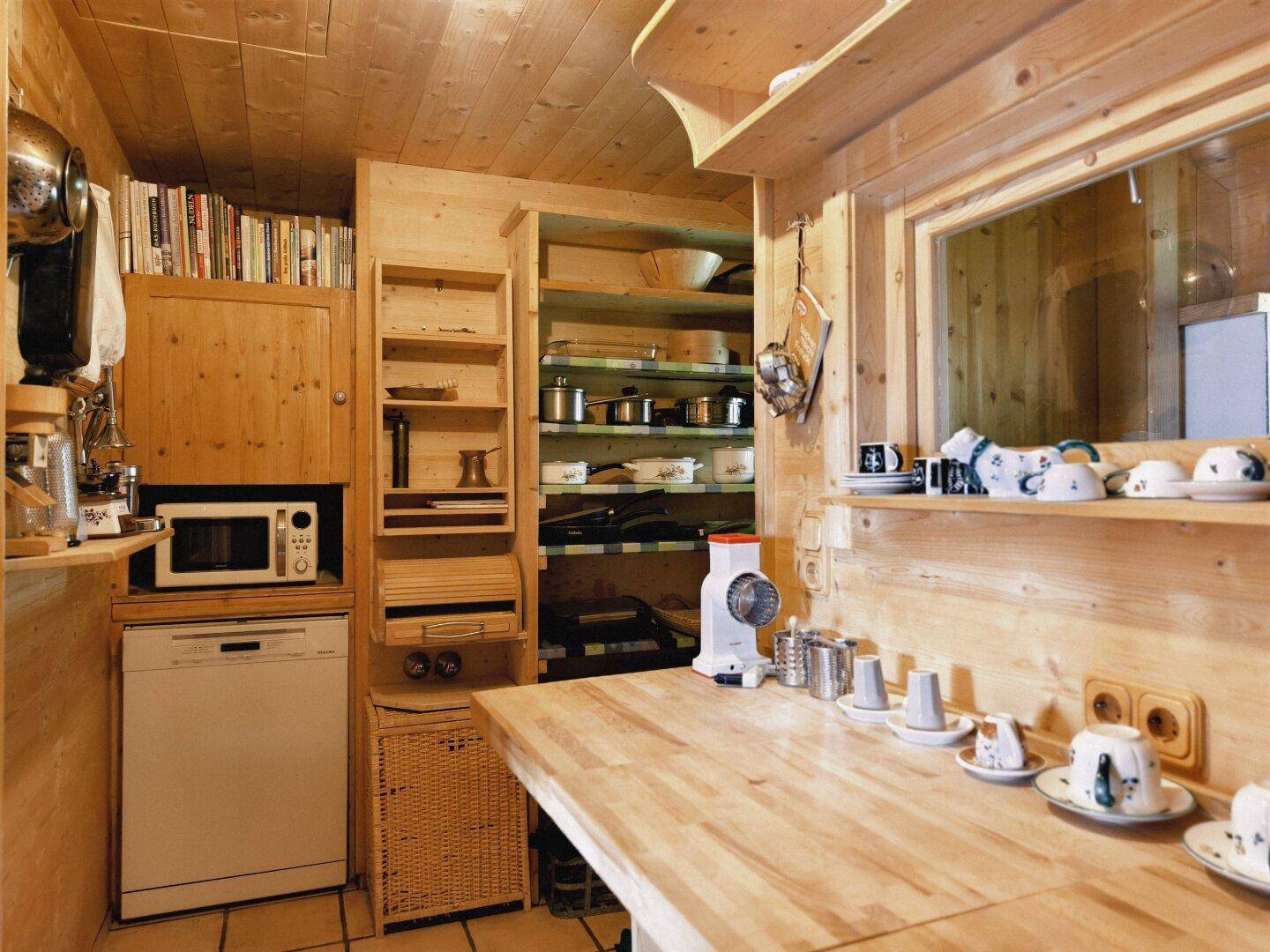 Rustikale Holzküche mit integrierten Geräten, offenem Regal und viel Stauraum.