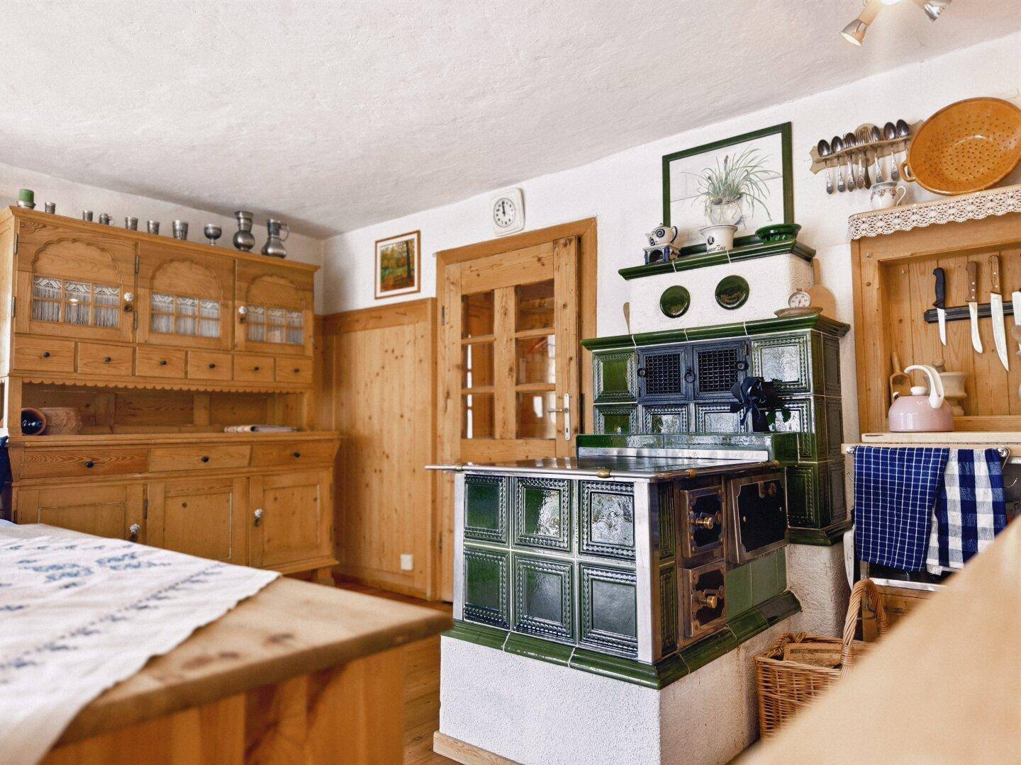 Traditionelle Küche mit grünem Kachelofen, Holzschränken und rustikalem Charme.