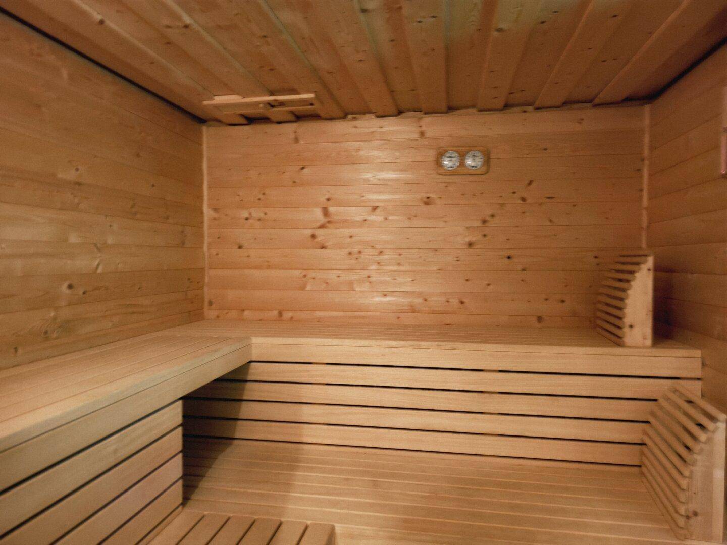 Geräumige Holzsauna mit Sitzbänken und traditionellem Design für Entspannung.