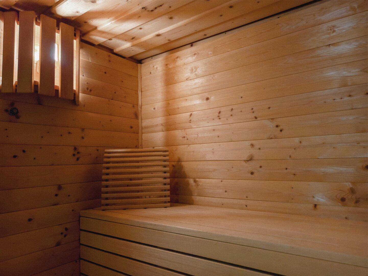 Detailansicht der Holzsauna mit Holzbänken und indirekter Beleuchtung.