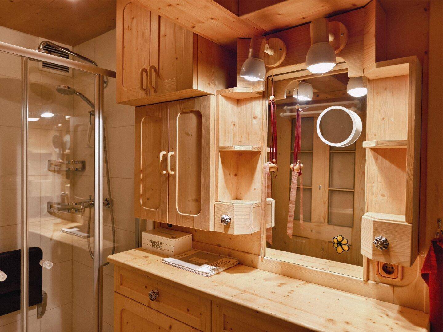 Rustikales Badezimmer mit Holzmöbeln, Spiegelfläche und Duschkabine.