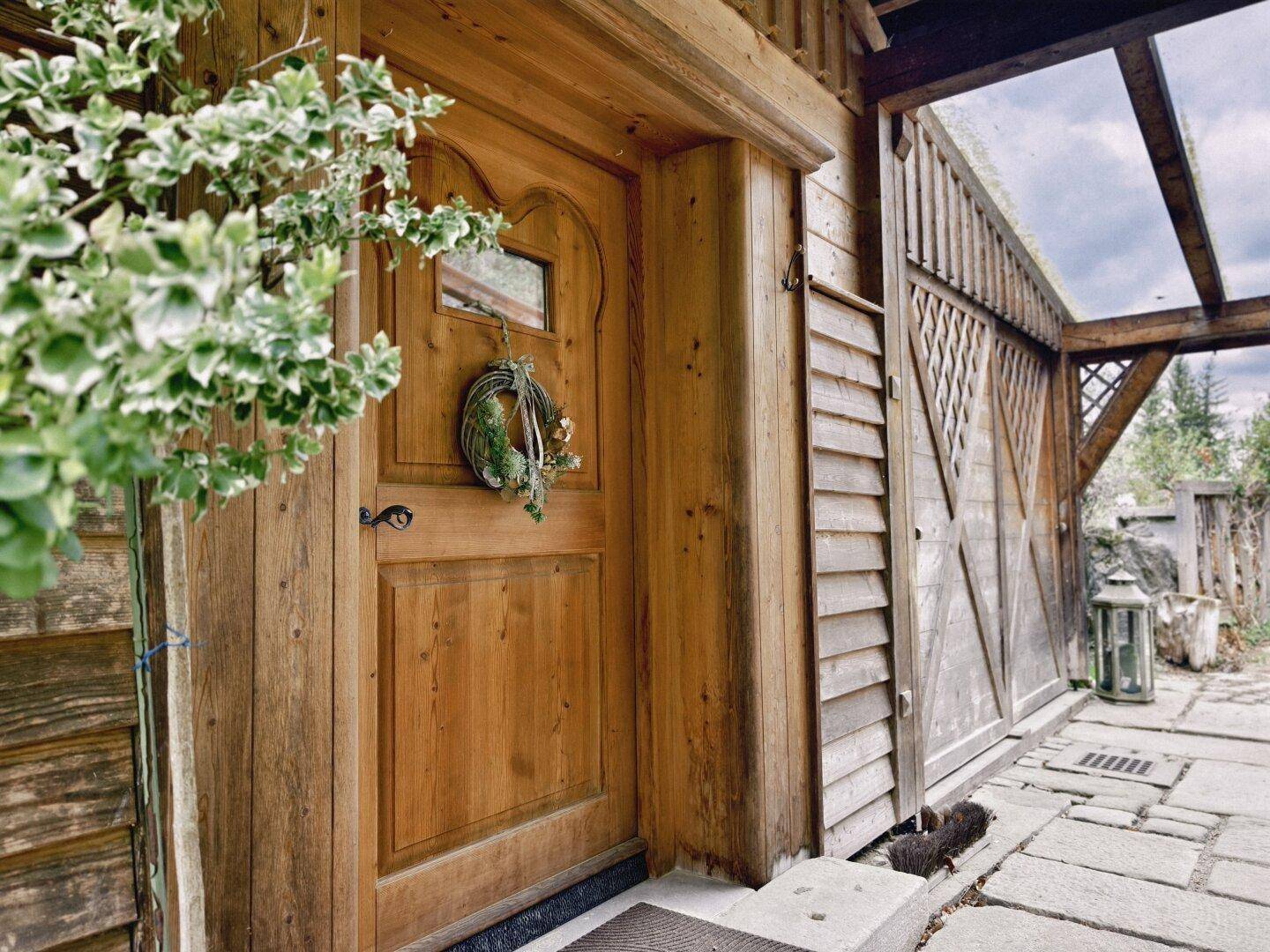 Eingangsbereich eines Holzhauses mit Holztür und rustikalem Charme.