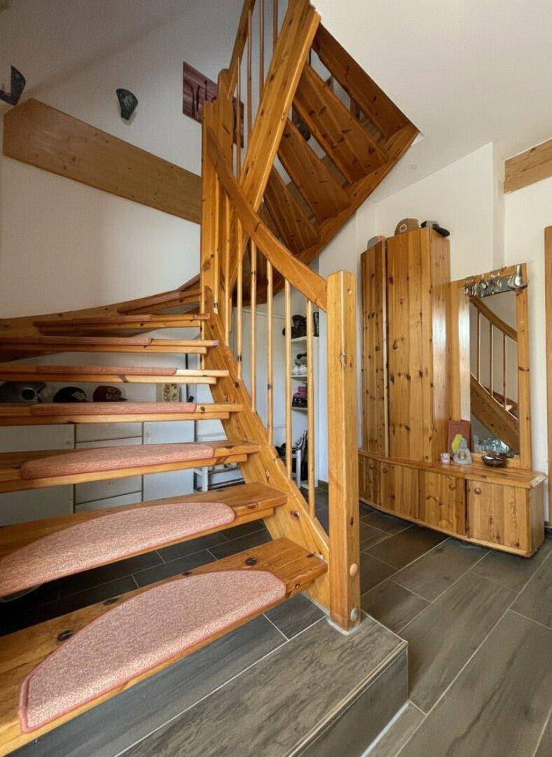 Heller Flur mit Holztreppe und passenden Holzmöbeln, die eine warme Atmosphäre schaffen.