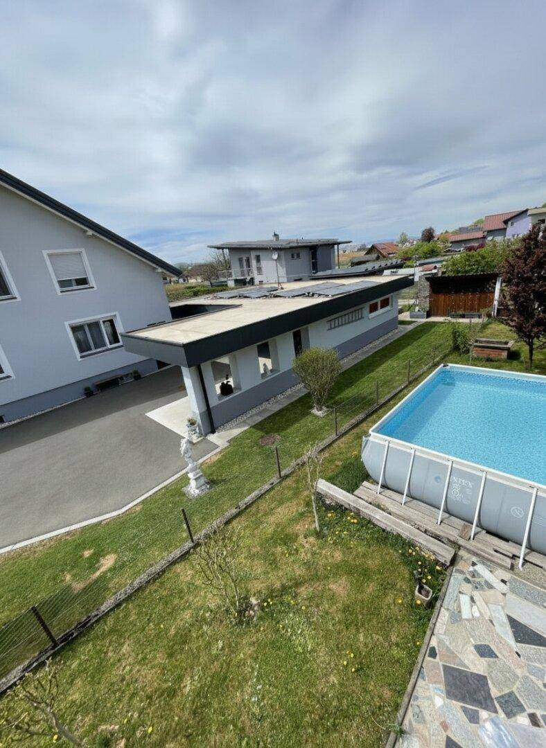 Überblick über das Anwesen mit Pool, Rasenfläche und angrenzenden Gebäuden.