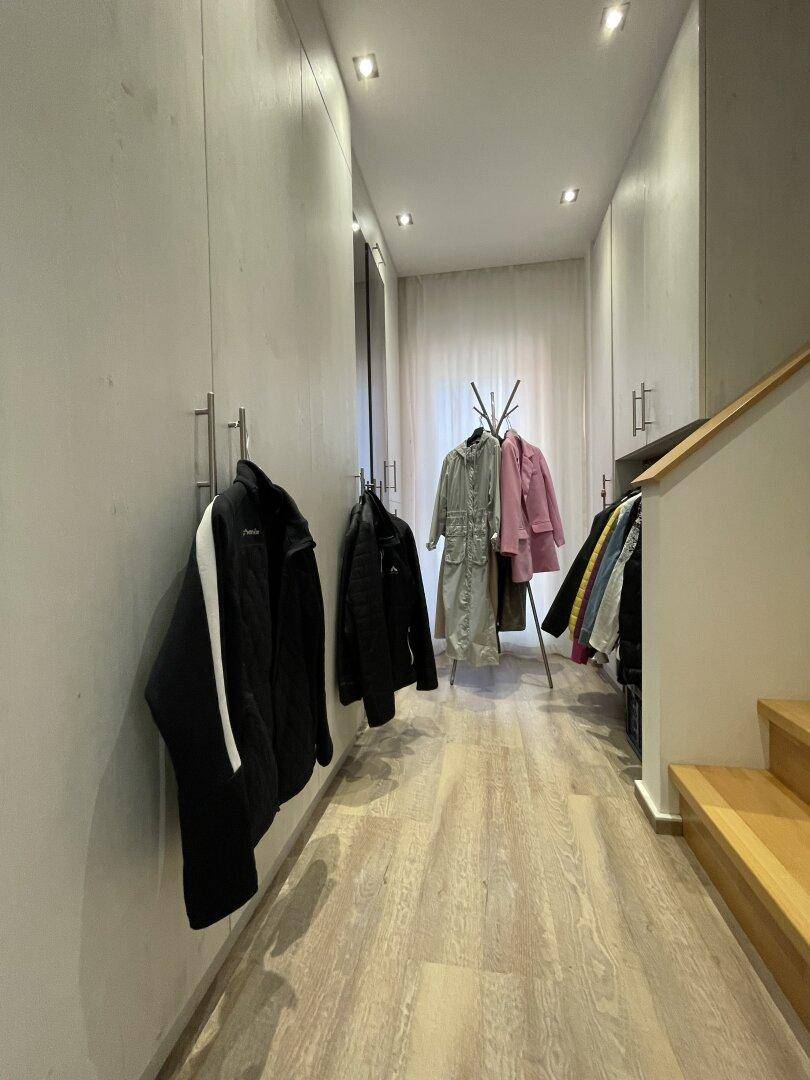 Langer Ankleidebereich mit Einbauschränken und Garderobe, führt zu weiteren Räumen.