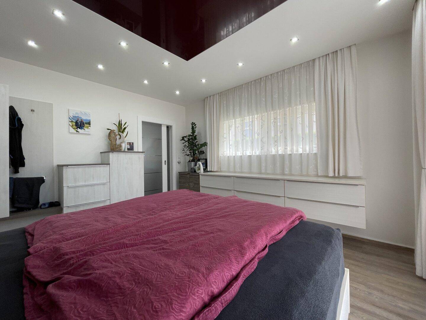 Gemütliches Schlafzimmer mit Blick vom Bett auf die Einbauschränke und das Fenster, das den Raum erhellt.