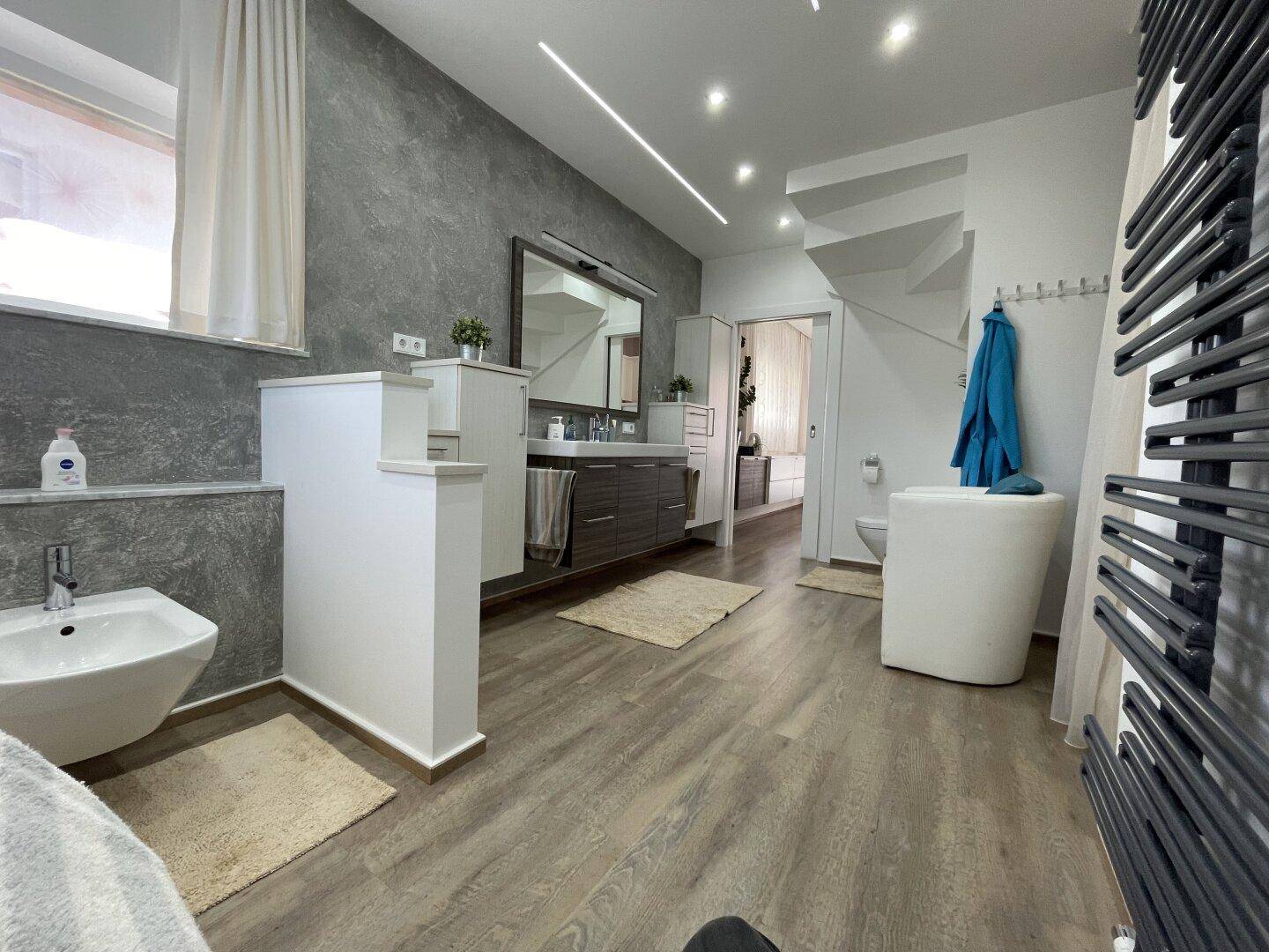 Großzügiges modernes Badezimmer mit Bidet, Waschtisch, wandhängendem WC und Handtuchheizkörper für Komfort.