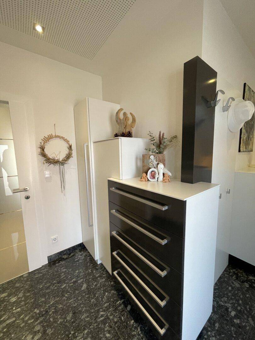 Detailansicht eines Flurs mit einem eleganten weiß-schwarzen Schrank und geschmackvollen Dekorationsgegenständen.