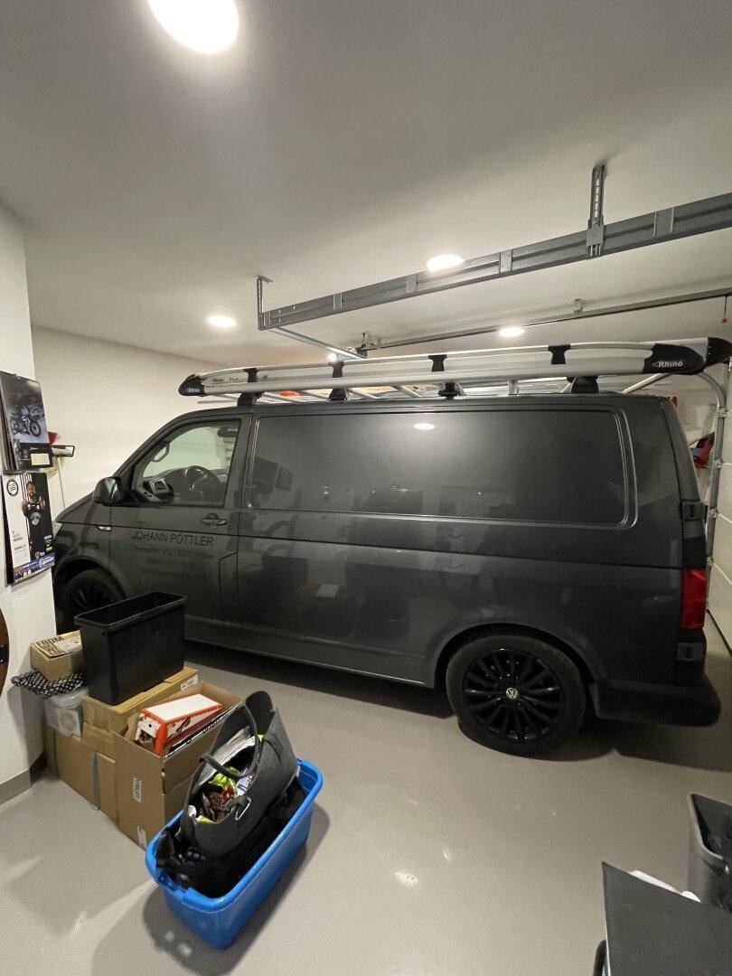 Innenansicht einer Garage mit einem geparkten Lieferwagen, Lagerkisten und dem Mechanismus des Garagentors.