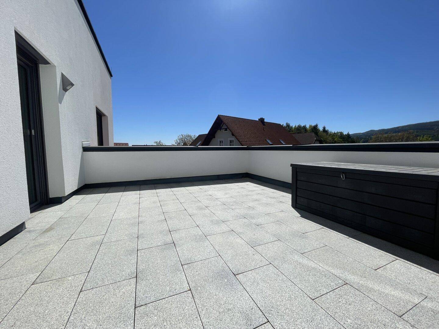 Geräumige, geflieste Terrasse mit viel Platz für Gestaltung und einem praktischen Stauraumkasten.