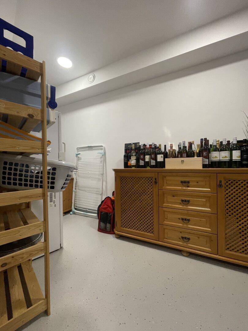 Lagerraum mit Weinregalen und einem Holzschrank, der zusätzlichen Stauraum für Haushaltsgegenstände bietet.