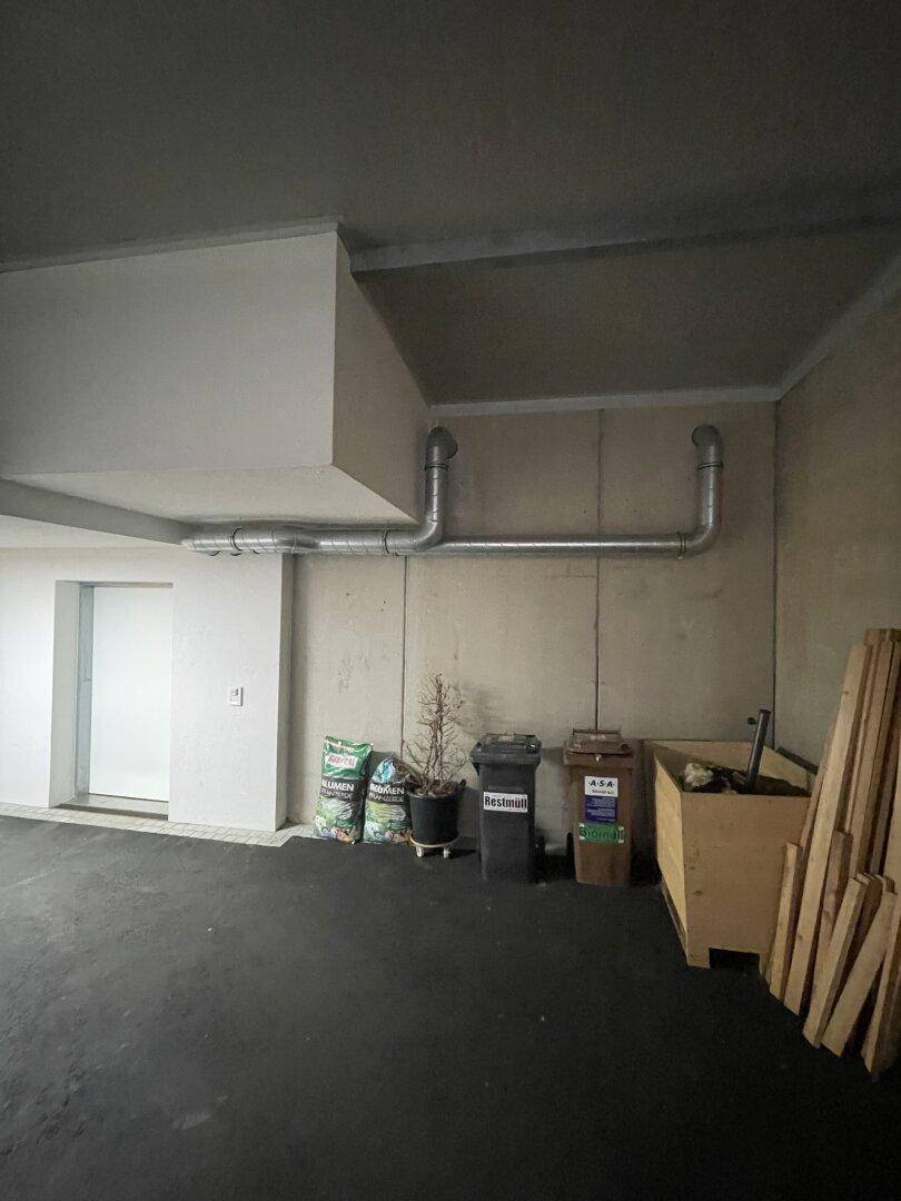 Tiefgarage mit Betonwänden und sichtbaren Rohrleitungen an der Decke, bietet viel Stauraum.