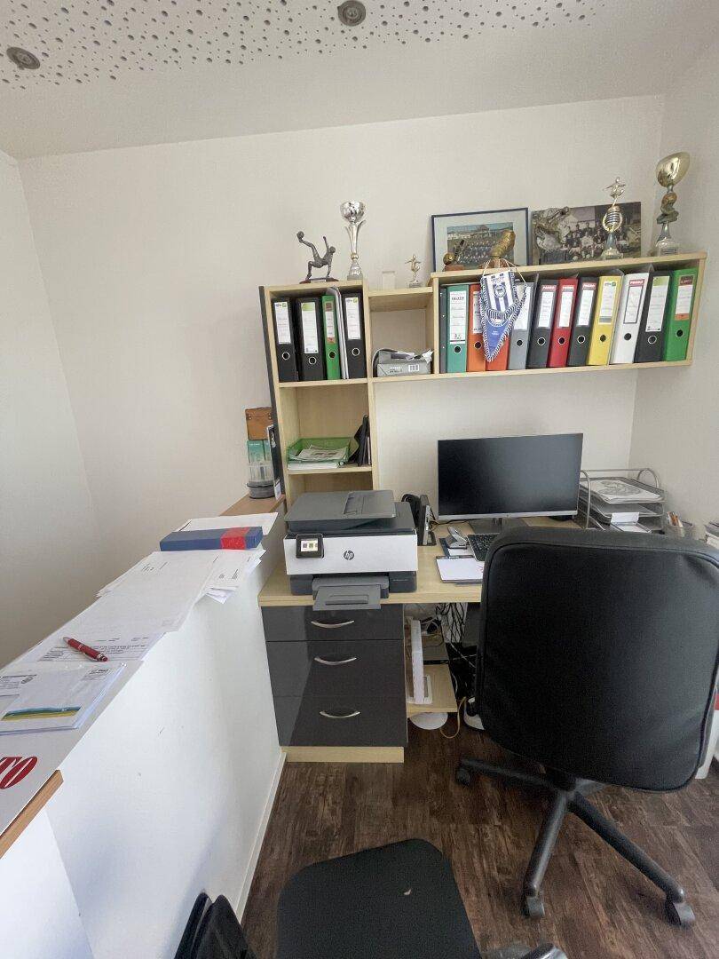 Funktionales Heimbüro mit Schreibtisch, Computer und Regalen für Akten, ausgestattet mit Laminatboden.