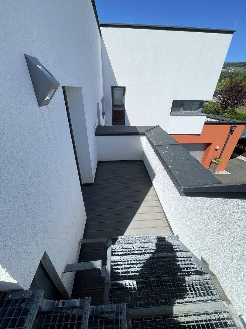 Moderne Architektur mit weißer Fassade und einer Außentreppe, die zu einem oberen Bereich führt.