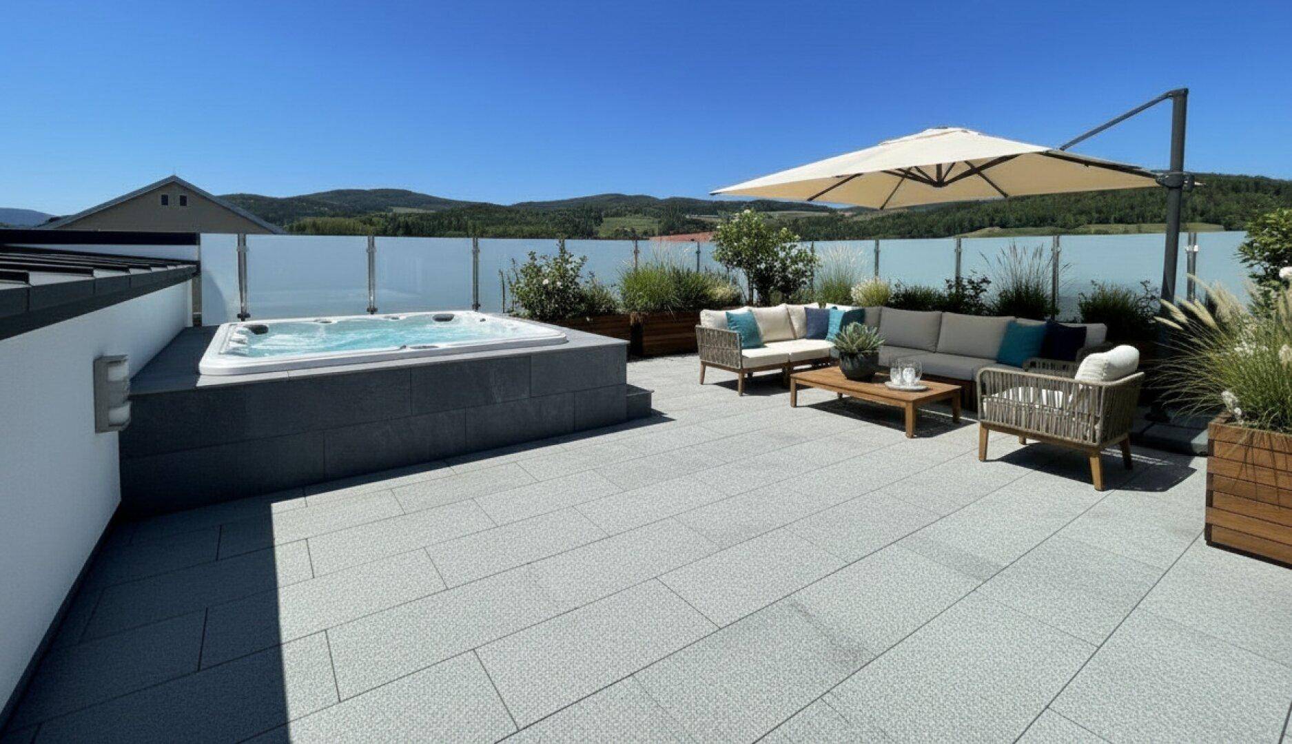 Großzügige Dachterrasse mit Whirlpool, bequemen Loungemöbeln und weitem Blick in die Landschaft.