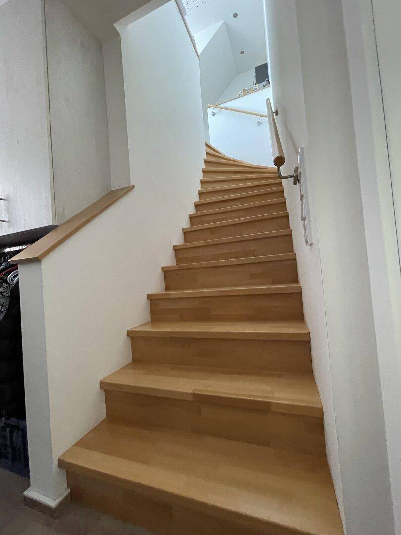 Helle Holztreppe mit modernem Geländer, die zu den oberen Etagen des Hauses führt.