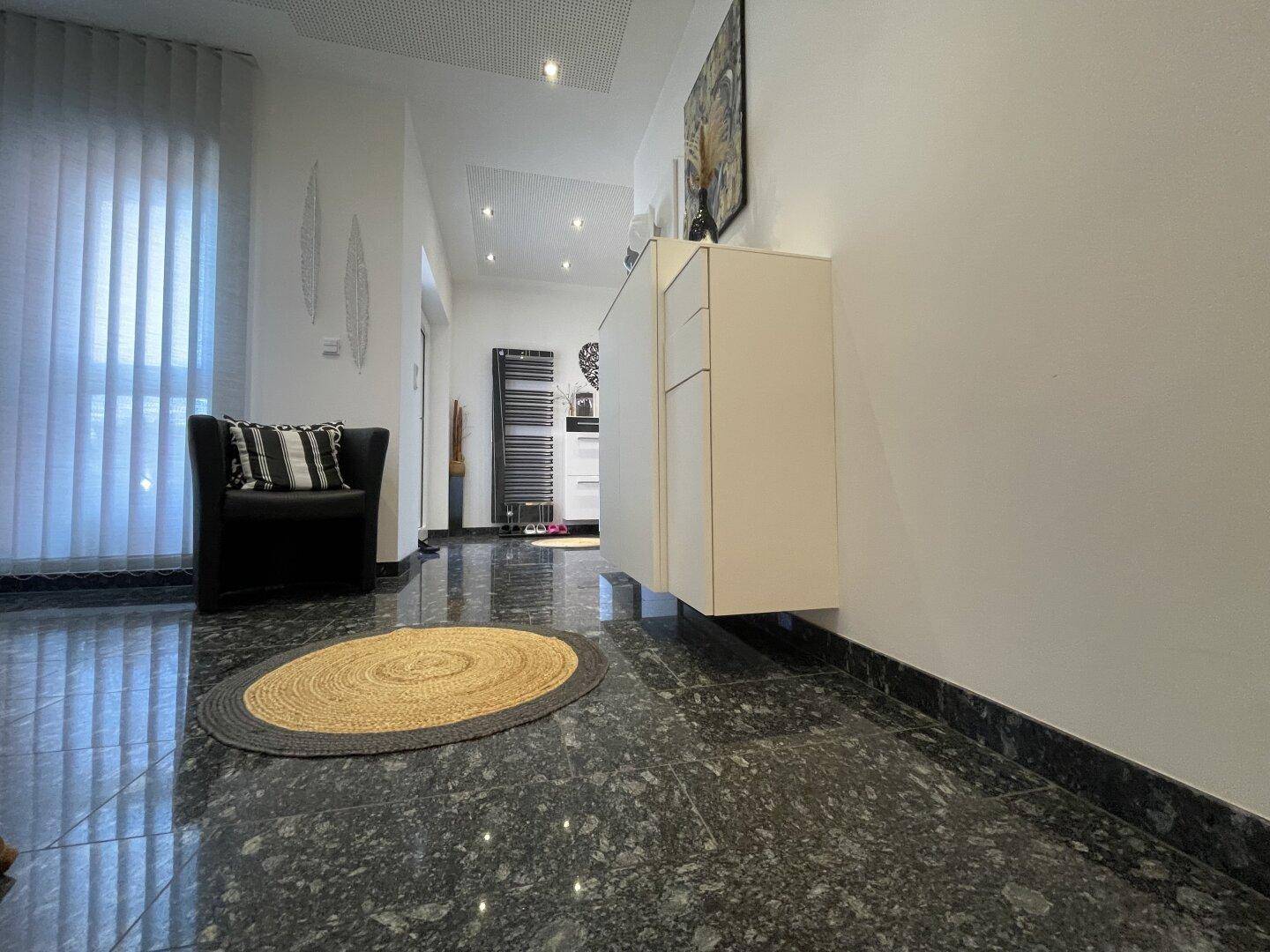 Eleganter Flur mit dunklem Granitboden, modernem Schrank und einem bequemen schwarzen Sessel.