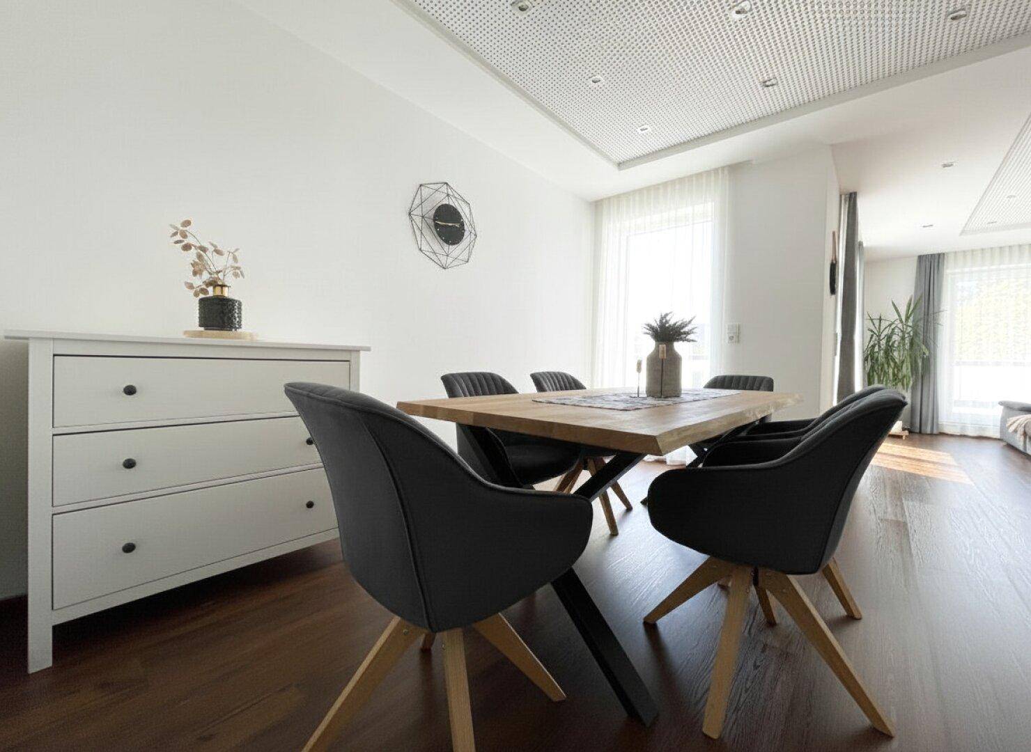 Moderner Essbereich mit einem Holztisch, schwarzen Stühlen und einer weißen Kommode, die den Raum ergänzt.