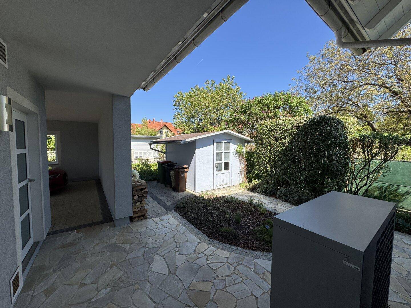 Kleiner Gartenschuppen und Wärmepumpe im gepflegten Gartenbereich des Hauses.