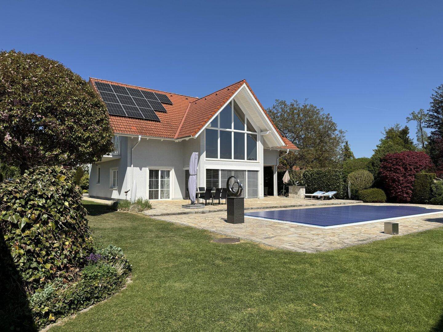 Großzügiger Garten mit Pool und Haus, umgeben von gepflegten Grünflächen und Bäumen.