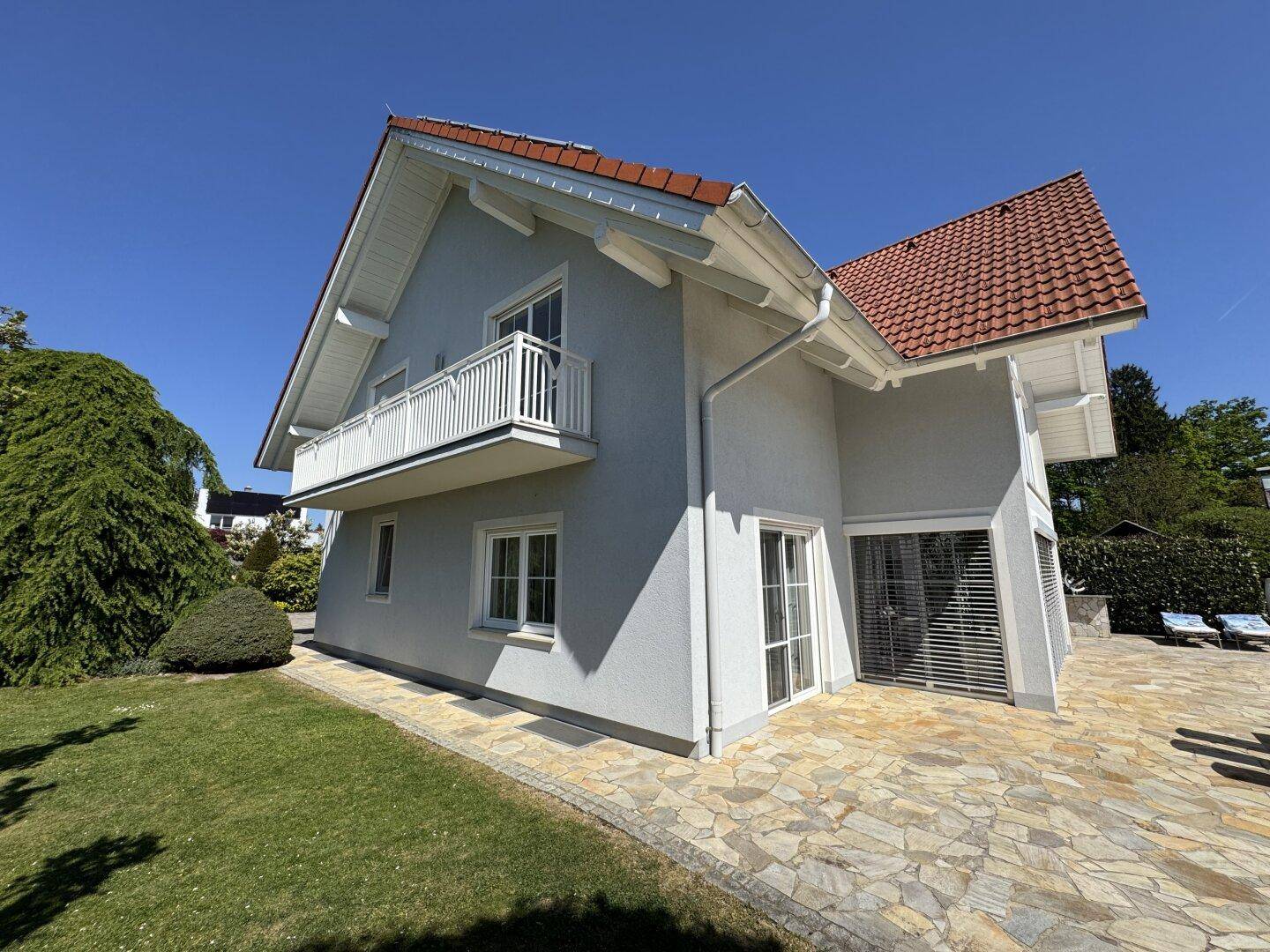 Seitliche Ansicht des Hauses mit Balkon und Zugang zum Gartenbereich.