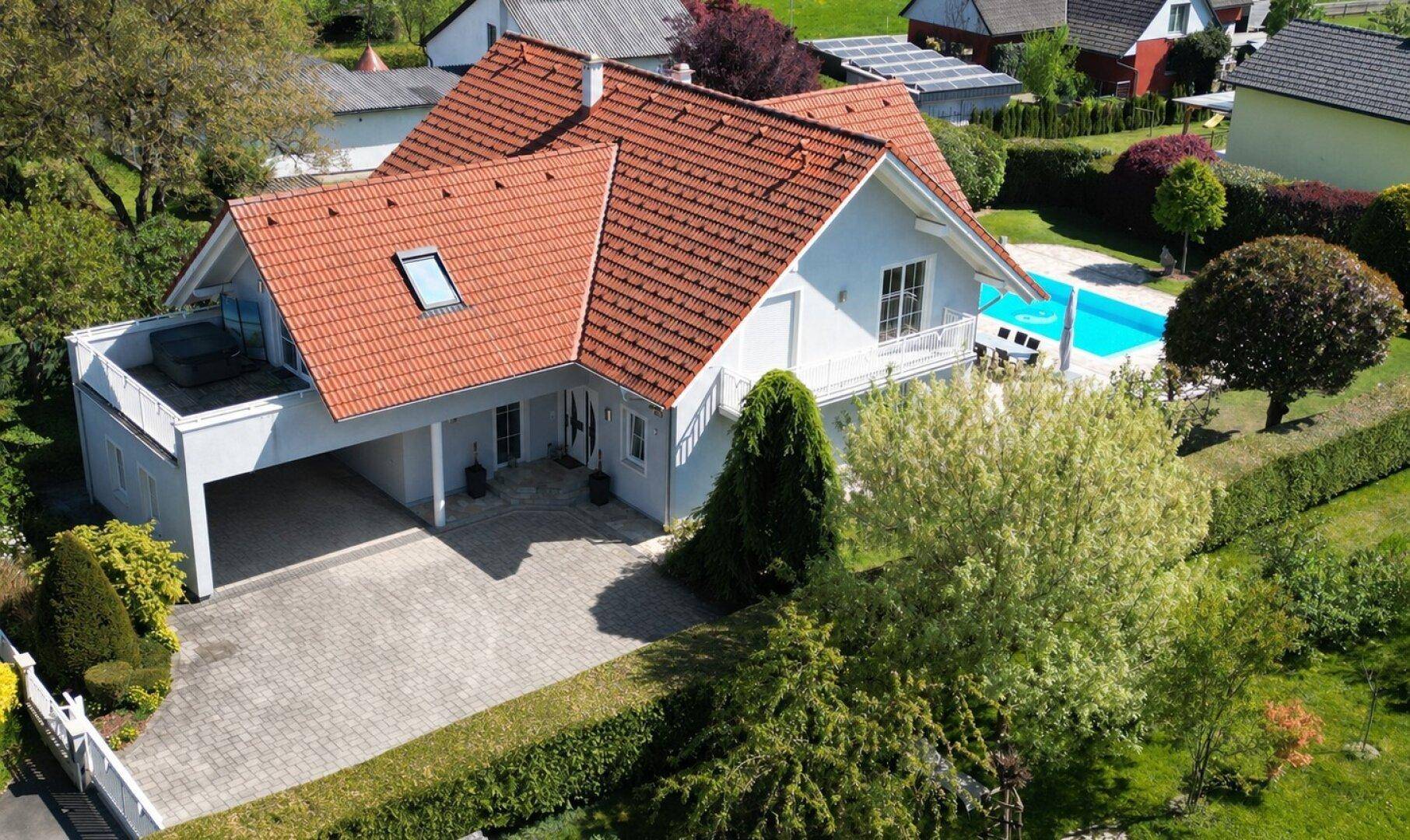Luftaufnahme des gesamten Anwesens mit Haus, Pool, Carport und weitläufigem Garten.