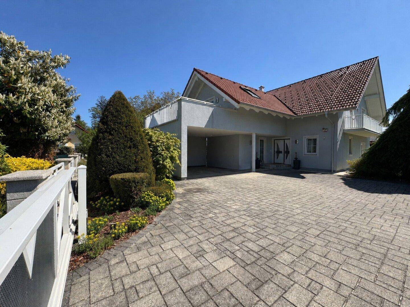 Großzügige Auffahrt und Carport vor dem modernen Einfamilienhaus mit gepflegtem Vorgarten.