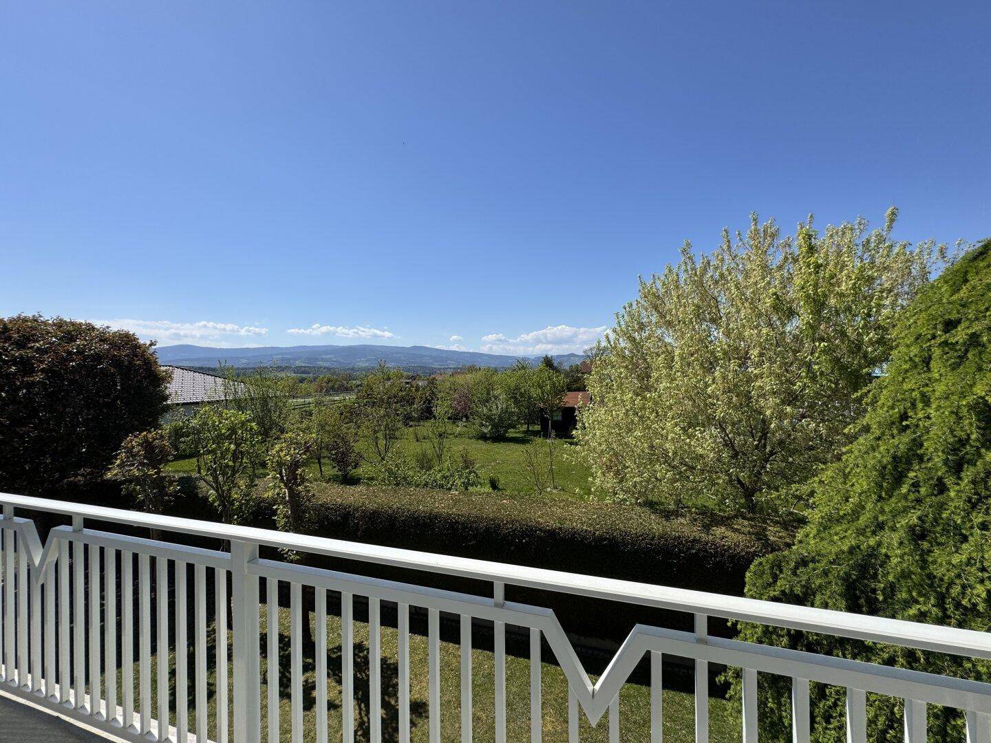 Weitläufiger Ausblick vom Balkon auf die grüne Landschaft und die umliegenden Berge.