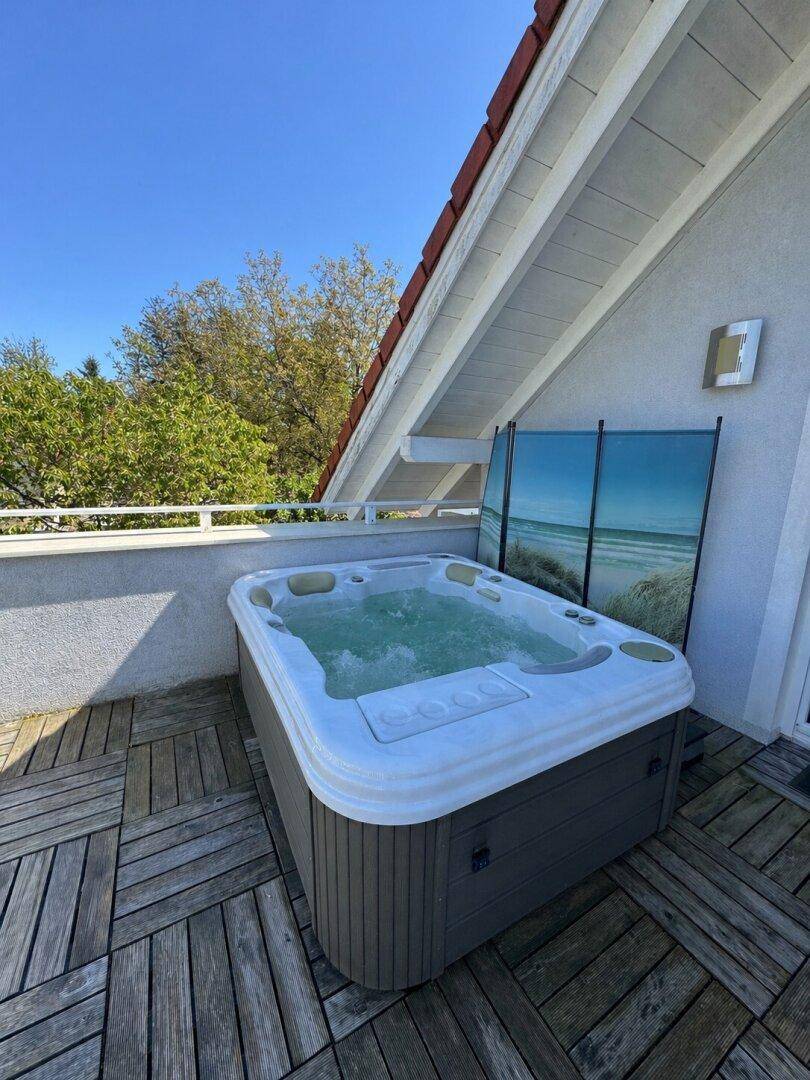 Entspannender Whirlpool auf dem Balkon mit Holzboden und Blick in die Natur.