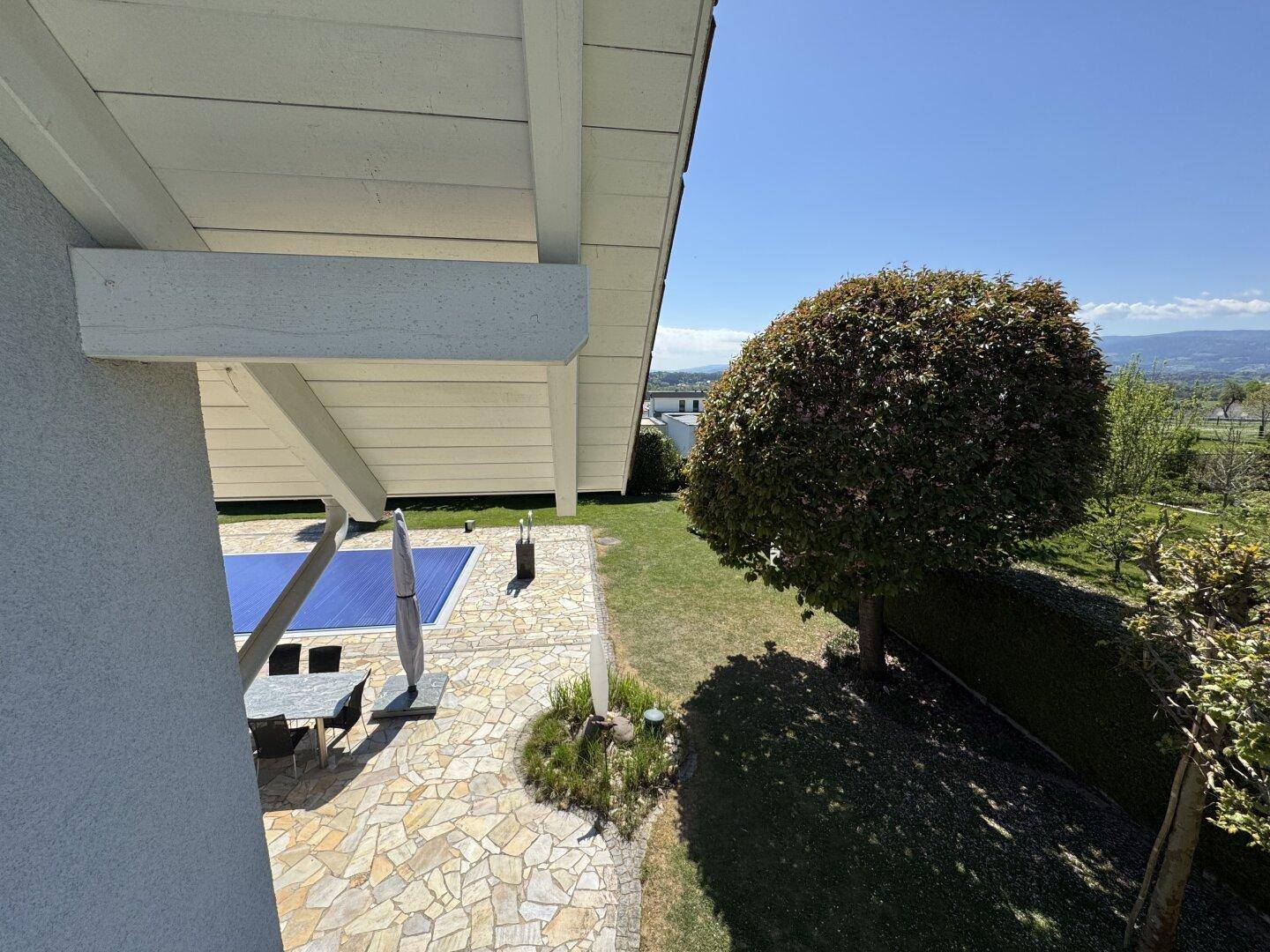 Blick von oben auf die Terrasse mit Gartenmöbeln und den abgedeckten Poolbereich.