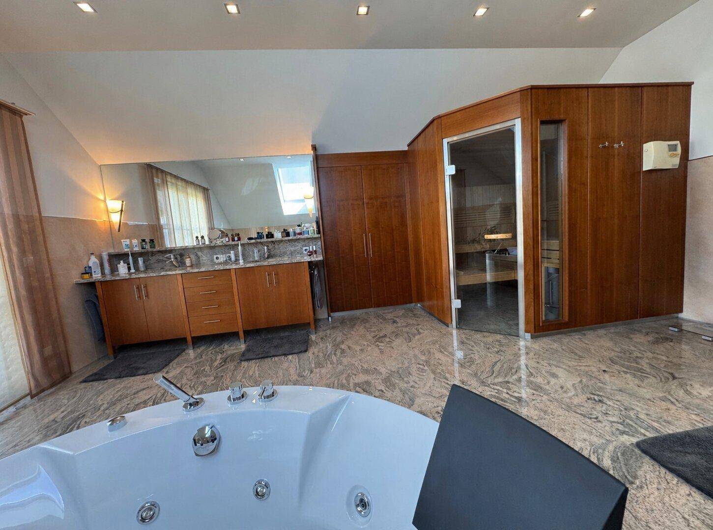 Luxuriöses Badezimmer mit Whirlpool, Sauna und Granitboden im Dachgeschoss.