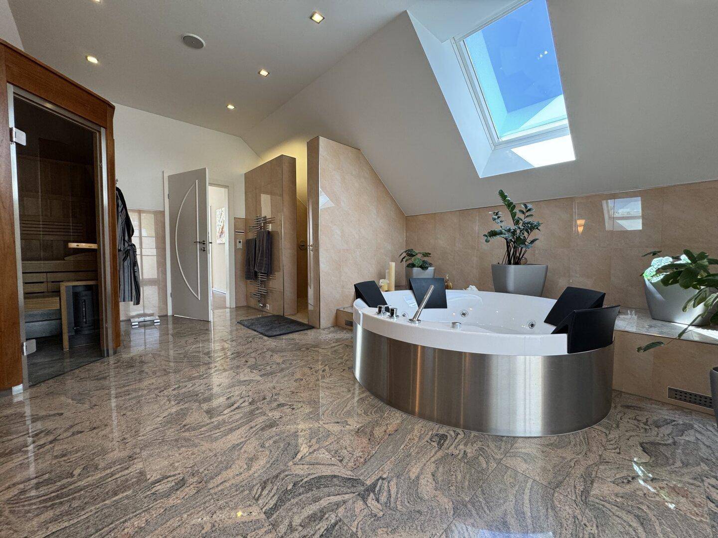 Exklusives Spa-Badezimmer mit freistehendem Whirlpool, Sauna und Dachfenster für viel Licht.